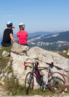 2 cyclistes arrêtés sur un rocher avec vue sur le Vercors